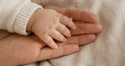 A baby's hand resting in a parent's open palm