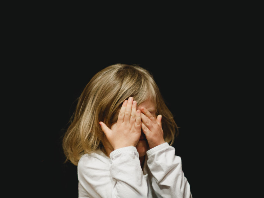 A child covering their face with their hands